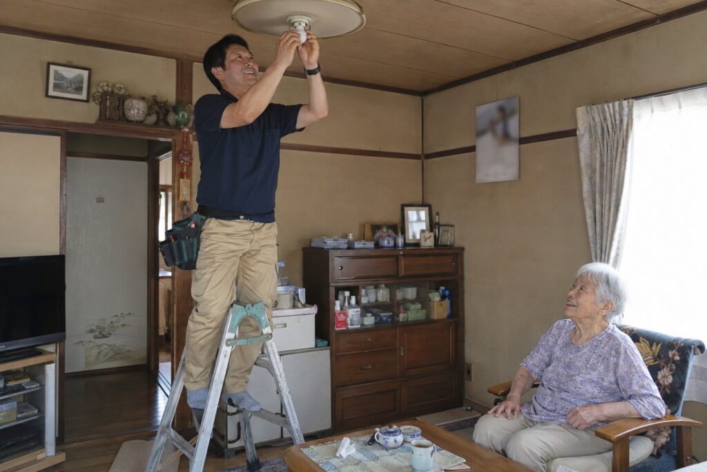 脚立に上って照明の電球を交換する様子